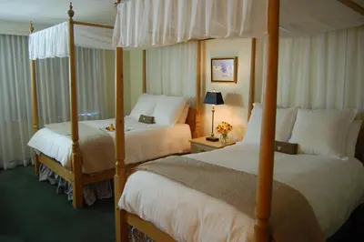 a hotel room with two beds and a canopy bed at The Simsbury Inn in Simsbury