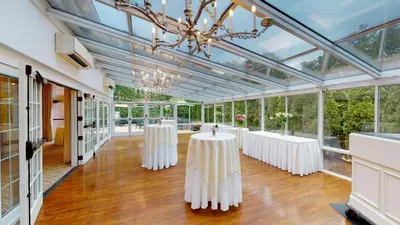 a conservatory with two tables in a room with windows at The Simsbury Inn in Simsbury