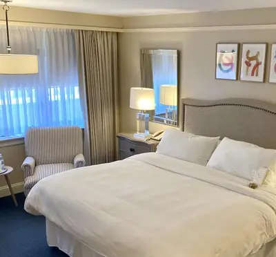 a hotel room with a large bed and a chair at The Simsbury Inn in Simsbury