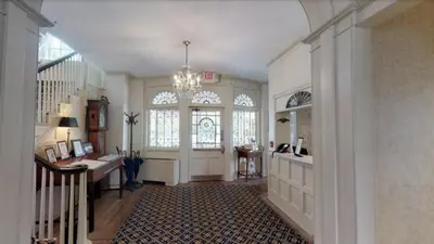 a living room with a chandelier and a hallway at Simsbury 1820 House in Simsbury