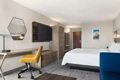 a hotel room with a bed and a desk and a chair at Holiday Inn Express & Suites East Greenbush Albany-Skyline by IHG in Rensselaer