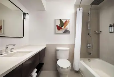 a white bathroom with a toilet and a sink at Sonesta White Plains Downtown in White Plains