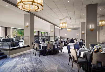a dining room with tables and chairs and a chandelier at Sonesta White Plains Downtown in White Plains