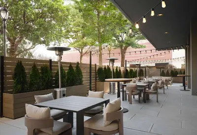 a restaurant with tables and chairs and trees at Sonesta White Plains Downtown in White Plains