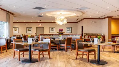 a restaurant with tables and chairs and a chandelier at Holiday Inn Plainview-Long Island by IHG in Plainview