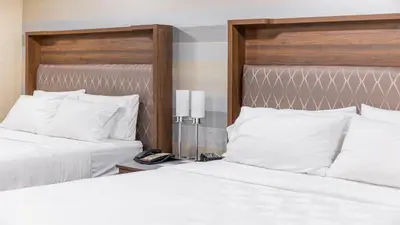 two beds in a hotel room with white pillows at Holiday Inn Plainview-Long Island by IHG in Plainview