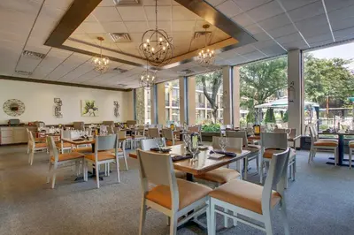 a dining room with tables and chairs and windows at Holiday Inn Westbury-Long Island by IHG in Carle Place