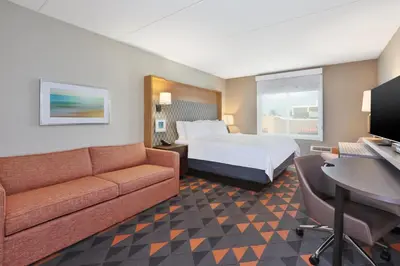 a hotel room with a bed and a couch at Holiday Inn Westbury-Long Island by IHG in Carle Place