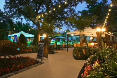 a patio with tables and umbrellas at night at Holiday Inn Westbury-Long Island by IHG in Carle Place