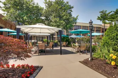 a patio with tables and chairs and umbrellas at Holiday Inn Westbury-Long Island by IHG in Carle Place