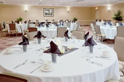 a large banquet room with white tables and chairs at Armoni Inn & Suites in Orangeburg