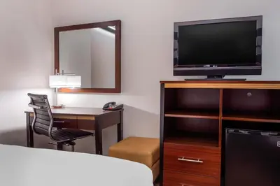 a hotel room with a bed and a desk with a television at Avion Inn Near LGA Airport, an Ascend Collection Hotel in Queens