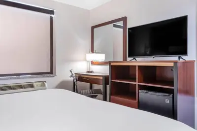 a hotel room with a bed and a desk and a television at Avion Inn Near LGA Airport, an Ascend Collection Hotel in Queens