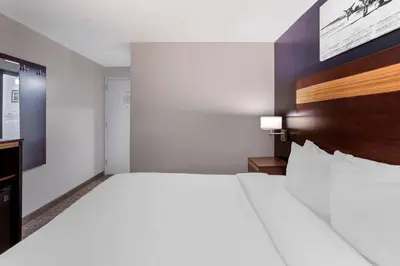 a bedroom with a large white bed with a wooden headboard at Avion Inn Near LGA Airport, an Ascend Collection Hotel in Queens