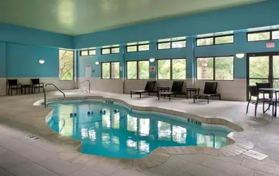 a swimming pool in a building with tables and chairs at Holiday Inn Express Great Barrington by IHG in Great Barrington