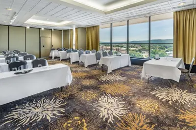 a conference room with tables and chairs and large windows at Holiday Inn & Suites Pittsfield-Berkshires by IHG in Pittsfield