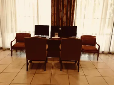 a table with chairs and a table with two computers on it at Holiday Inn & Suites Pittsfield-Berkshires by IHG in Pittsfield