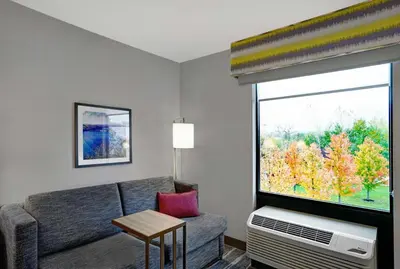 a living room with a couch and a large window at Hampton Inn Utica in Utica