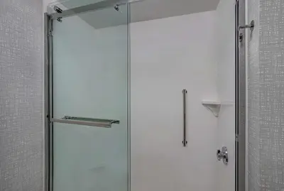 a shower with a glass door in a bathroom at Hampton Inn Utica in Utica