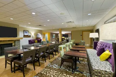 a restaurant with tables and chairs and a fireplace at Hampton Inn Danbury in Danbury