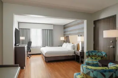 a hotel room with a bed and a desk and chairs at Hotel Trilogy Albany Airport, Tapestry Collection by Hilton in Latham