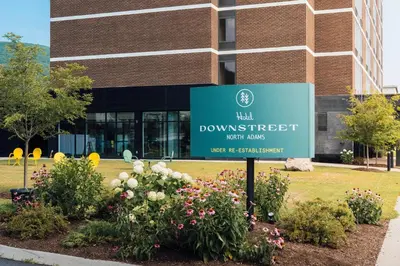 a sign in front of a building with flowers at Hotel Downstreet, an Ascend Collection Hotel in North Adams