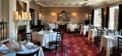 a dining room with white tables and chairs and a fireplace at The Inn At Fox Hollow Hotel in Woodbury