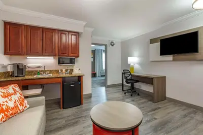 a living room with a couch and a kitchen with a desk at Comfort Inn & Suites Hadley - Amherst in Hadley