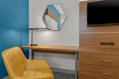 a desk with a television and a yellow chair at Holiday Inn Express Hotel & Suites West Coxsackie by IHG in West Coxsackie