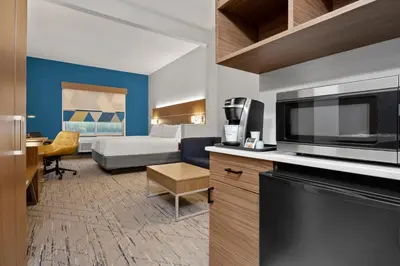 a hotel room with a bed and a kitchen with a microwave at Holiday Inn Express Hotel & Suites West Coxsackie by IHG in West Coxsackie