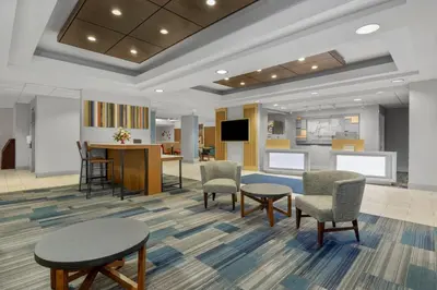 a waiting room with chairs and tables and a tv at Holiday Inn Express Hotel & Suites West Coxsackie by IHG in West Coxsackie