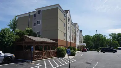 a building with a gazebo in front of a parking lot at Candlewood Suites-West Springfield by IHG in West Springfield