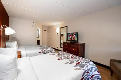 a hotel room with two beds and a flat screen tv at Red Roof Inn Meriden - CT in Meriden