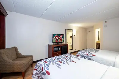 a bedroom with a bed and a chair and a television at Red Roof Inn Meriden - CT in Meriden