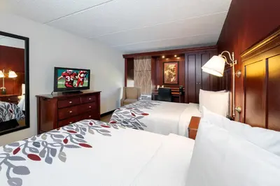 a hotel room with two beds and a flat screen tv at Red Roof Inn Meriden - CT in Meriden