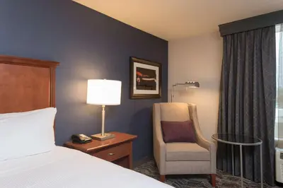 a hotel room with a bed and a chair and a lamp at DoubleTree by Hilton Schenectady in Schenectady