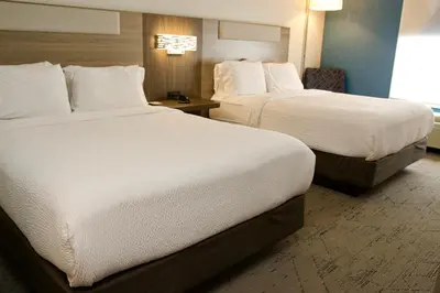 two beds in a hotel room with white sheets at Holiday Inn Express & Suites Albany Airport Area - Latham by IHG in Latham