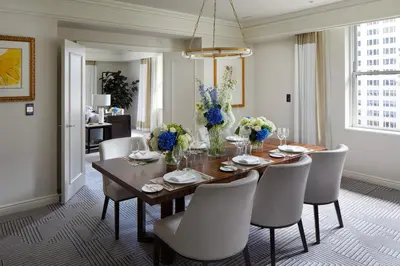 a dining room with a wooden table and white chairs at The Peninsula New York in New York