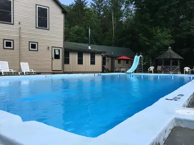 a swimming pool with blue water in front of a house at Slide Mountain Forest House in Oliverea