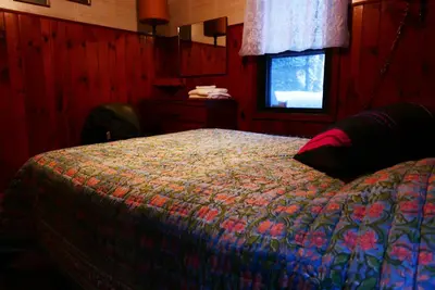 a bedroom with a bed with a colorful blanket and a window at Slide Mountain Forest House in Oliverea