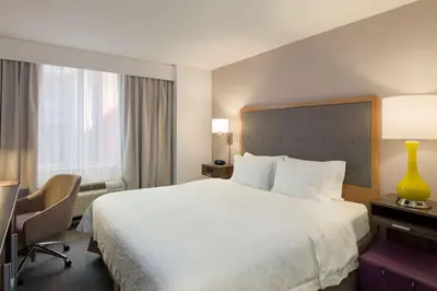 a hotel room with a large white bed and a desk at Hampton Inn Manhattan - Times Square South in New York