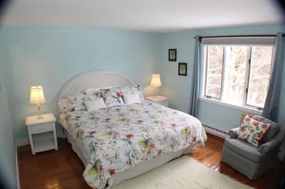 a bedroom with a bed and a chair and a window at The Inn at Quail Run in Wilmington
