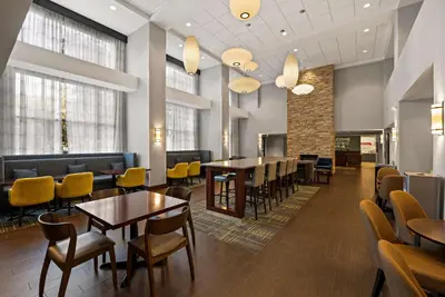a waiting room with tables and yellow chairs at Hampton Inn & Suites Poughkeepsie in Spackenkill