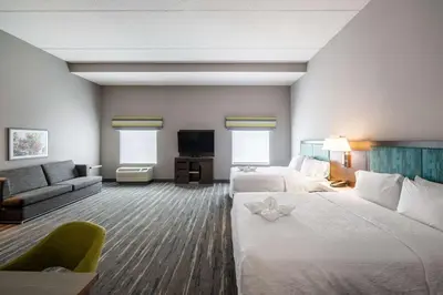 a hotel room with two beds and a couch at Hampton Inn & Suites Poughkeepsie in Spackenkill