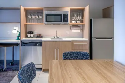 a kitchen with a refrigerator and a table and chairs at Home2 Suites by Hilton Saratoga Malta in Malta