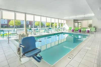 a swimming pool with a chair and tables and chairs at Home2 Suites by Hilton Saratoga Malta in Malta