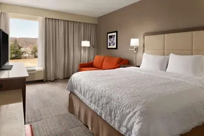 a hotel room with a bed and a chair and a window at Hampton Inn Denville-Rockaway-Parsippany in Denville