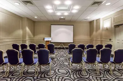 a conference room with chairs and a white screen at Wyndham Southbury in Southbury