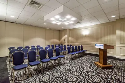 a conference room with blue chairs and a podium at Wyndham Southbury in Southbury