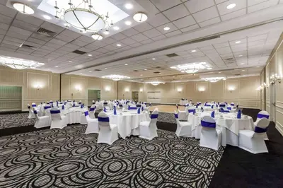 a banquet hall with white tables and chairs and a chandelier at Wyndham Southbury in Southbury